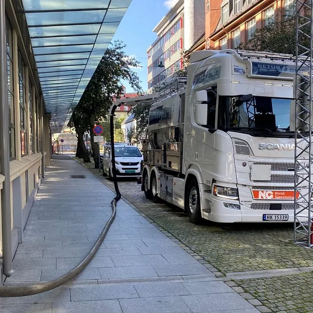 Hvit tankbil foran bygg